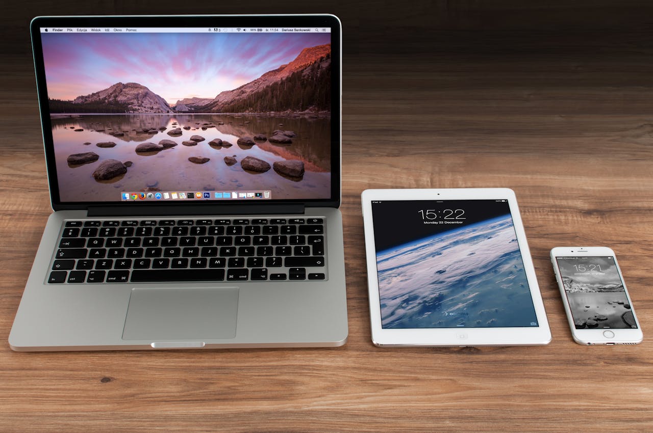Usługi Modern workspace showcasing Apple laptop, tablet, and smartphone on a wooden desk.