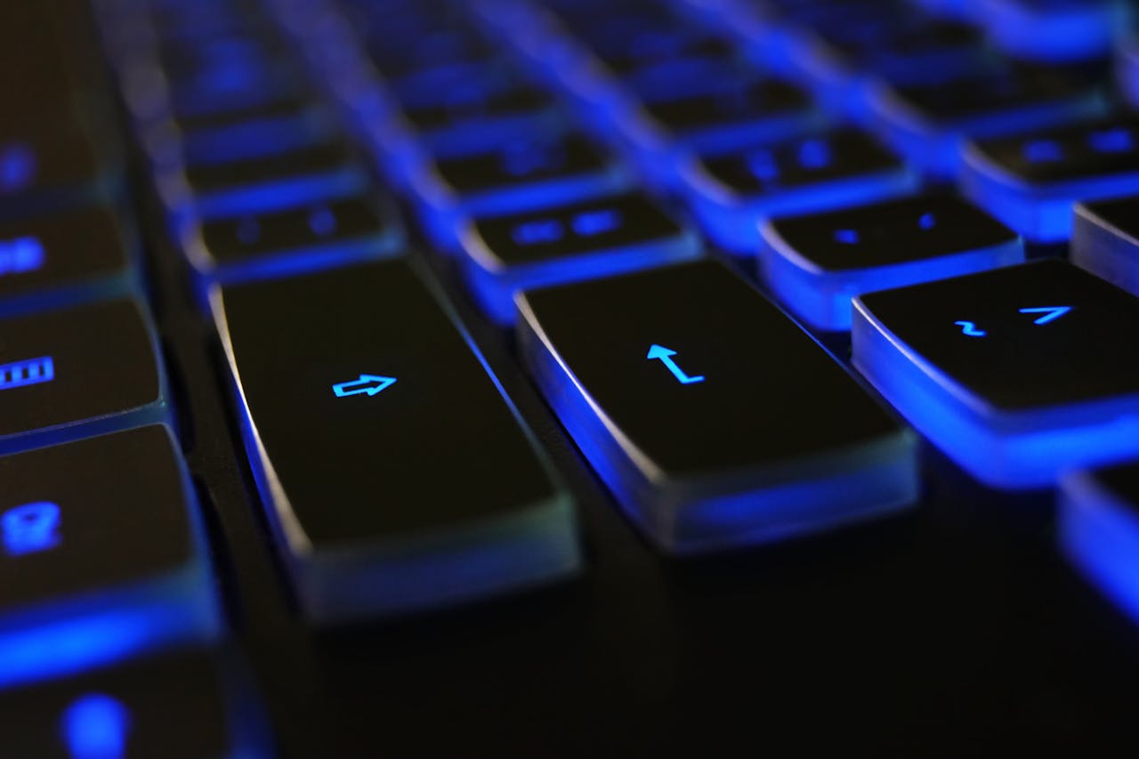 Usługi Detailed image of a computer keyboard with blue LED backlighting, highlighting keys.